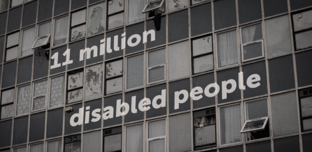 Text reading “11 million disabled people” is displayed across the windows of a deteriorating high-rise building, emphasizing the scale of disability and the urgent need for accessible, safe housing.