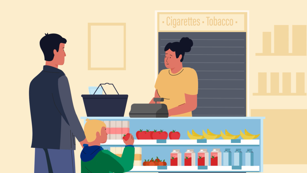 A child holds an apple while shopping with an adult at a grocery store counter, with fresh produce displayed and a closed tobacco cabinet in the background.