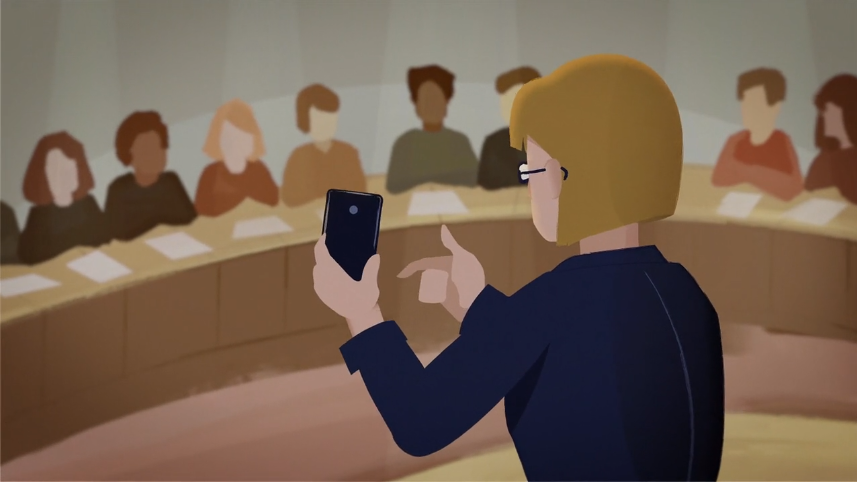 A woman holds up a smartphone while addressing a diverse group in a circular conference setting.