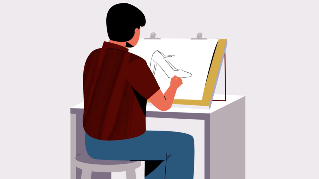 Man sitting at a drafting table sketching a high-heeled shoe with pencil on a tilted board.
