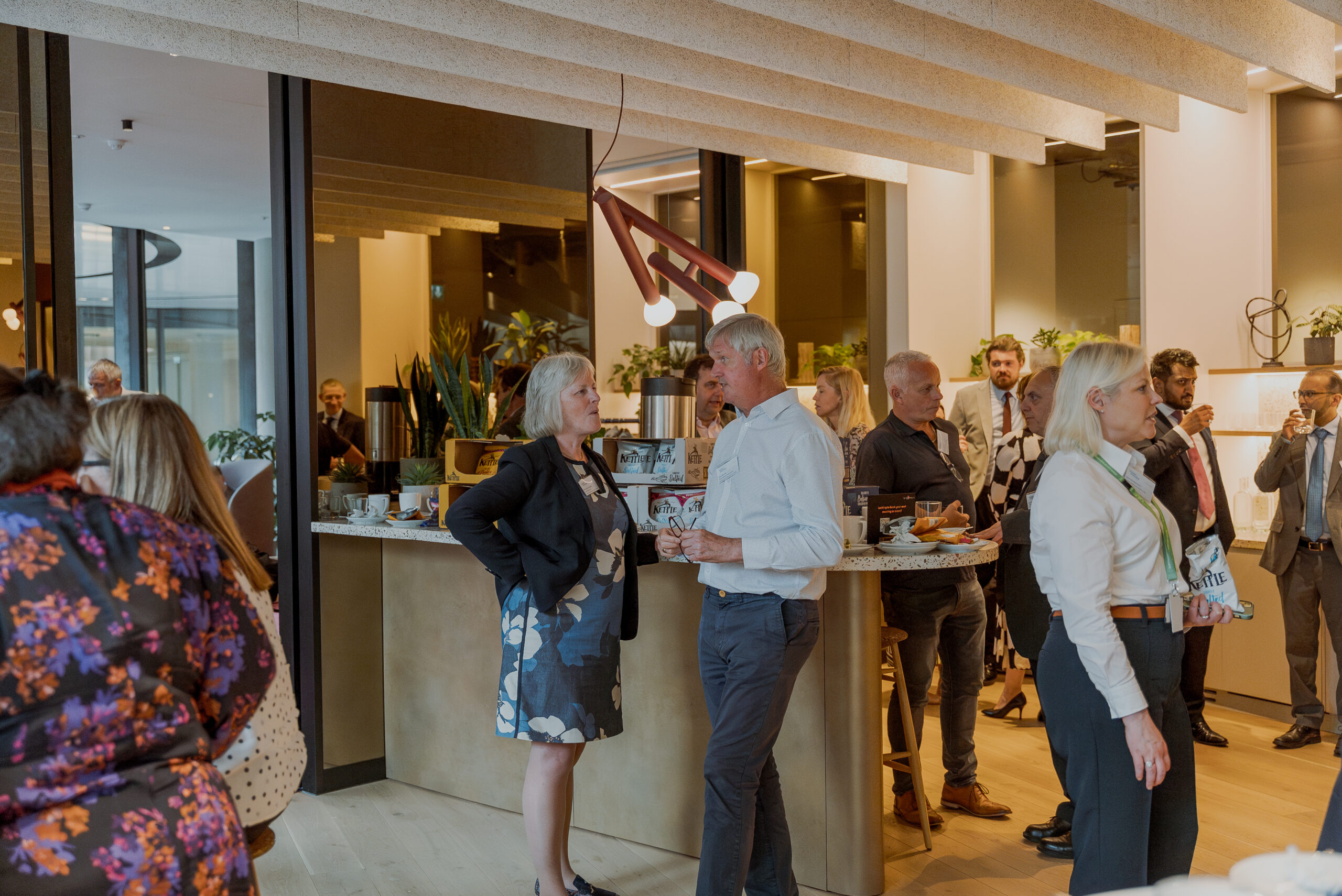 People networking and enjoying refreshments in a modern lounge area during a conference break.