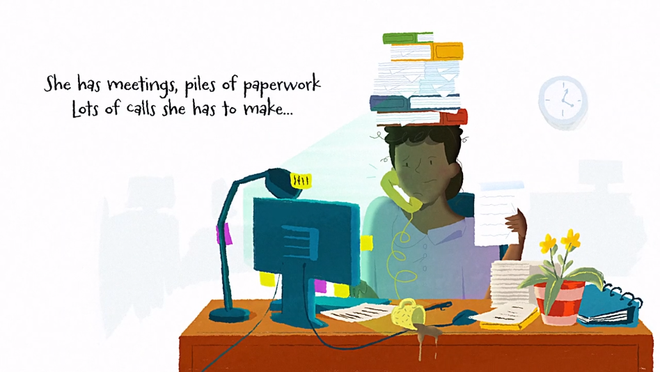 A woman sits at a cluttered desk, talking on the phone with books stacked on her head and paperwork everywhere.