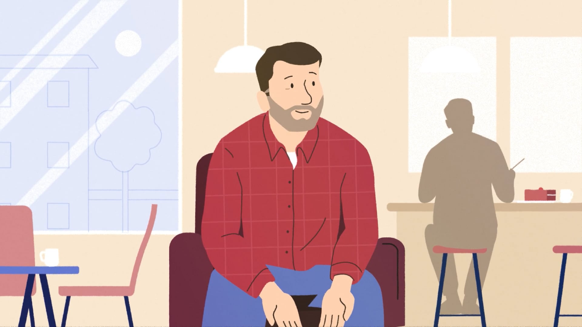 A man in a red check shirt sits in a café talking about his experience, symbolising social prescribing and mental health support.